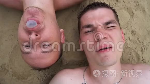 还有两个年轻人躺在海滩上，嚼口香糖，吹泡泡，对着镜头微笑