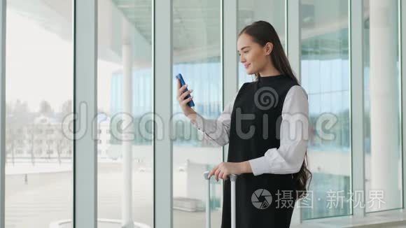 女游客在国际机场航站楼携带行李使用智能手机。 语音识别短信命令