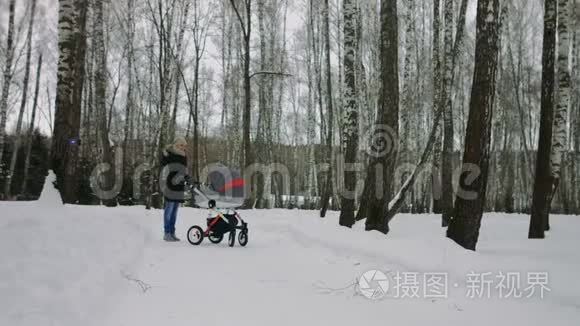 妈妈在冬天和婴儿车一起散步视频