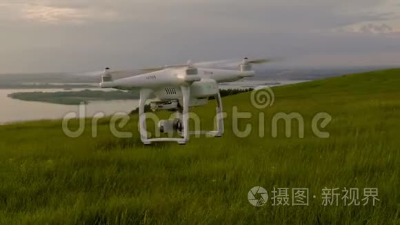 白色的无人机带着绿色的草飞过山坡，日落时被移到远处