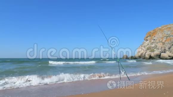 钓鱼竿矗立在沙滩上。 高清慢镜头。