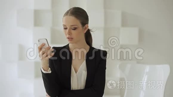 穿黑色正式服装的漂亮女人使用智能手机。 她在打电话。