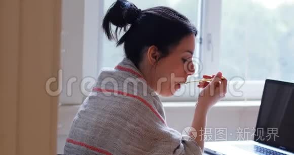 女士在吃早餐时看笔记本电脑视频