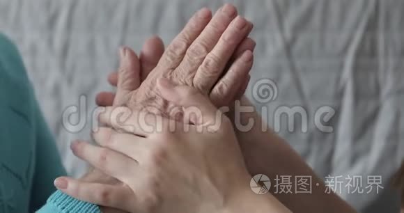 一个年轻的女人正在抚摸她祖母`皱纹的手。