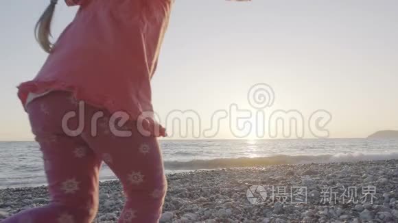 小女孩跑到海滩上迎接太阳，高兴地跳起来