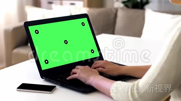 女性用绿色屏幕在笔记本电脑上打字