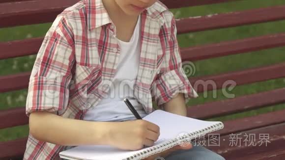 小男孩在长凳上的笔记本上画画