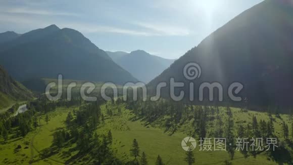 空中景在日落柔和的光线下飞越松树林山河和乡村道路。 山区