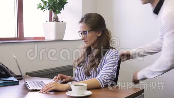 年轻的经理在现代办公室工作，看着笔记本电脑屏幕，说话。
