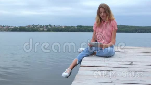 女人在平板电脑前轻敲，坐在湖边慢动作