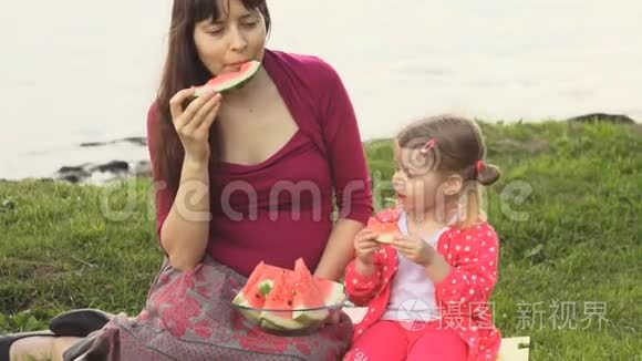 母亲和女儿在夏天在海边野餐吃西瓜。