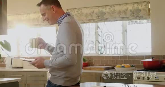 男子在厨房喝咖啡时使用手机视频