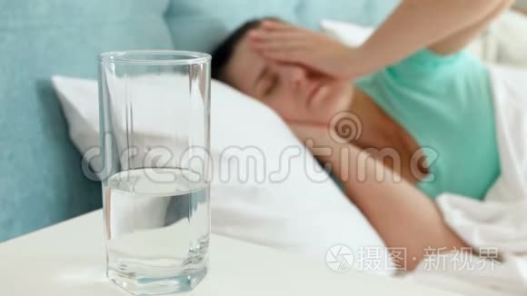 4k片头痛的年轻女子躺在床上，喝着玻璃水