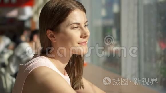 一幅美丽梦幻的年轻女子坐在靠近窗户的咖啡馆的桌子前思考的肖像。 美食广场