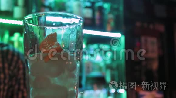 关闭酒吧玻璃和调酒师在酒吧柜台上的绿色灯光背景。
