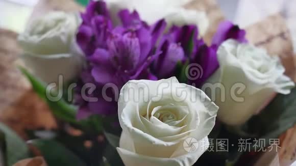 特写镜头上的一束束美丽的白花玫瑰正站在一个节日礼物的女人`室内