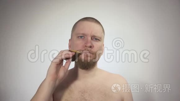 男人梳理他的红色胡须，白色背景上的木制梳子。