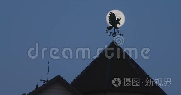 月亮在夜空中飞过建筑物的屋顶视频