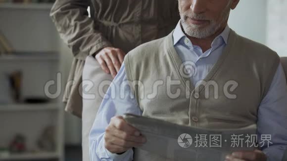 男性退休人员看报纸，女性从背后拥抱，充满爱意