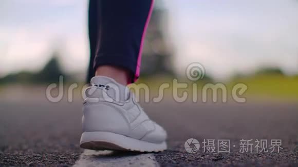 女选手开始跑。 在公路上穿白色运动鞋的跑步者腿