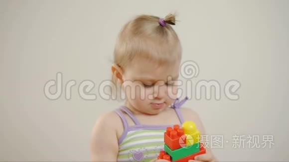 小女孩在彩色积木里玩耍，坐在白色的背景上。 孩子和玩具。
