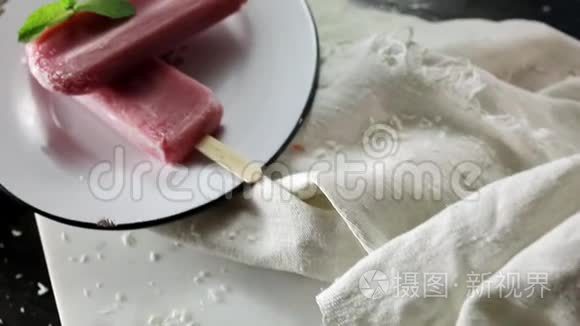 合上草莓冰淇淋。 缓慢的食物运动。 两根棍子在黑色的木制背景板上。 在炎热的夏天帮忙