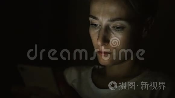 疲倦悲伤的女人晚上用手机。