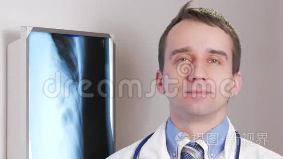 一位年轻的医生看着相机微笑。 背景下悬挂患者x线.. 带领带的衬衫