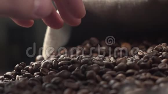 香气扑鼻的烤咖啡豆被放在桌子上，手在慢动作中测试品质视频的预览图