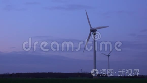 在下萨克森州汉诺威郊区的一个晚上，三台现代风力涡轮机在一片土地上产生可持续能源