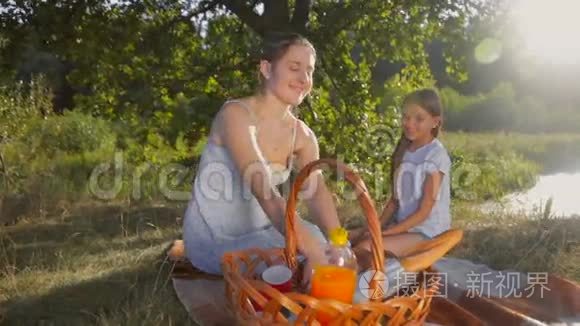 快乐的微笑妈妈在公园野餐时给女儿苹果