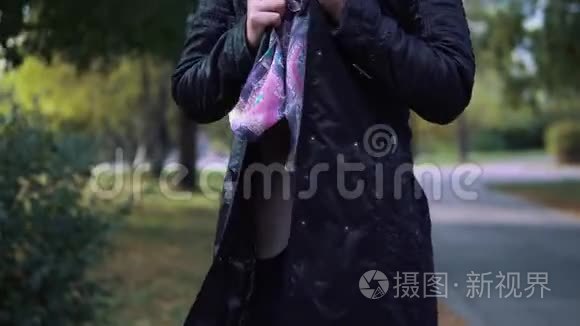 那女孩在秋天的公园里冻僵了。年轻女子裹着围巾，在他手上呼气取暖