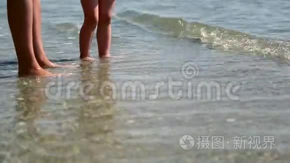 妈妈在海里和婴儿脚。 浪洗儿童腿