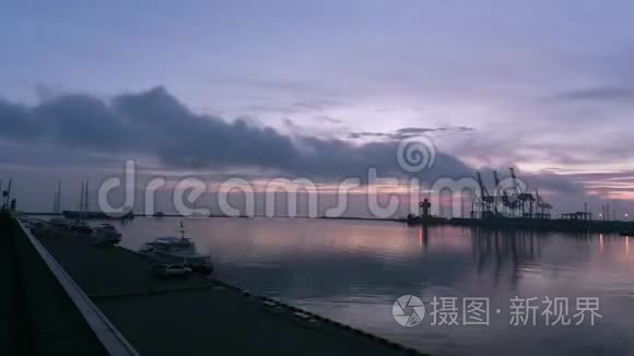 海港的黎明。 船和游艇在码头的波浪上摇摆，一艘大型货船从港口游出