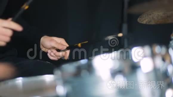 鼓声特写音乐家穿着黑色衬衫的人用鼓槌敲击鼓和鼓式盘子，注意力集中，注意力不集中