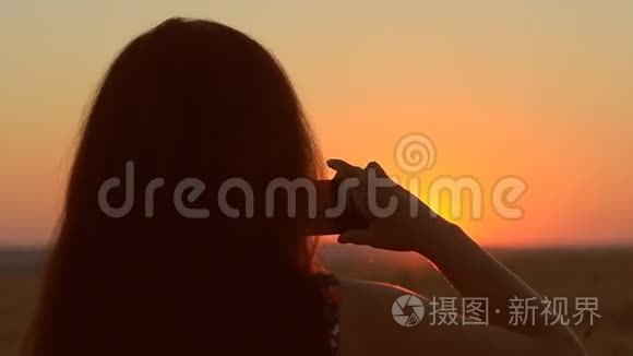 女孩带着手机在日落图上打着电话，夕阳美丽的黄昏景观。