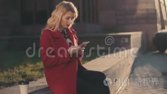 穿着红大褂的女商人坐在商务中心附近，用手机（phablet）。稳定的凸轮射击。