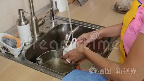 漂亮的女人在厨房的水槽里洗碗视频