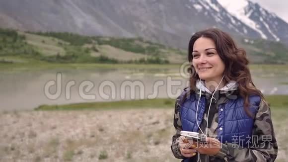 女游客戴着耳机在群山和风景的背景下跳舞。 旅游观光