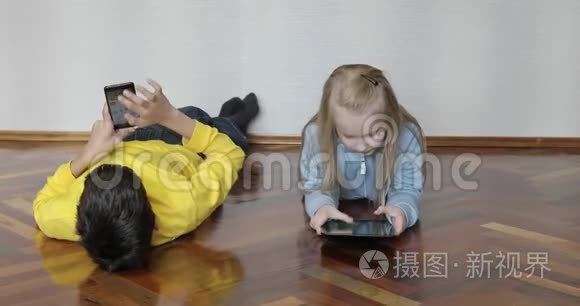 4一个男孩和一个女孩躺在地板上玩小玩意。