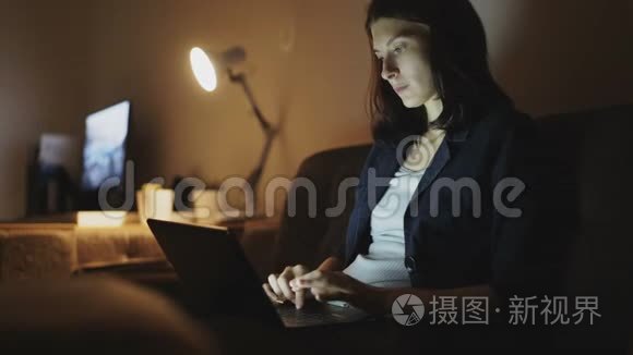 年轻集中的妇女晚上用手提电脑和打字
