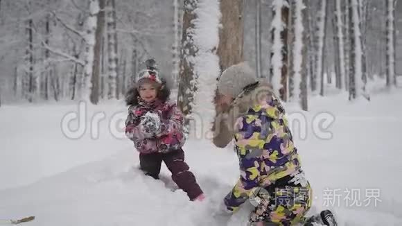 小女孩和她年轻的母亲在公园的户外雪地里玩耍。 快乐的孩子喜欢冬天。 很漂亮