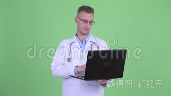 快乐的帅哥医生想着笔记本电脑视频