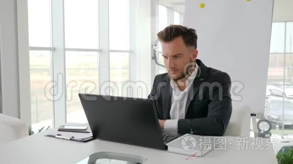 现代办公室年轻老板的电话交谈，成功的商人在互联网上的笔记本电脑上工作