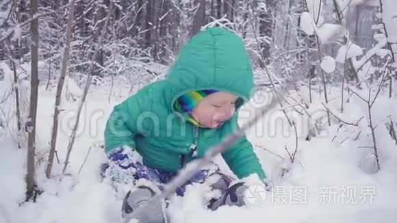 快乐的一岁男孩坐在冬天的森林里笑。用万向节制作