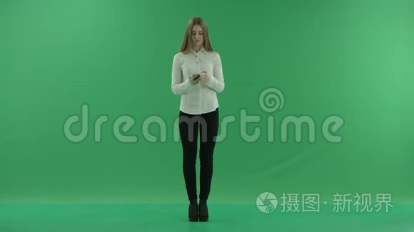 快乐的商业女人在用她的手机说话。 她穿着正式的衣服：白衬衫和白裤子