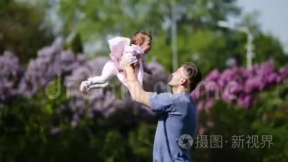 快乐的父亲抱着小女婴在公园里一起玩。