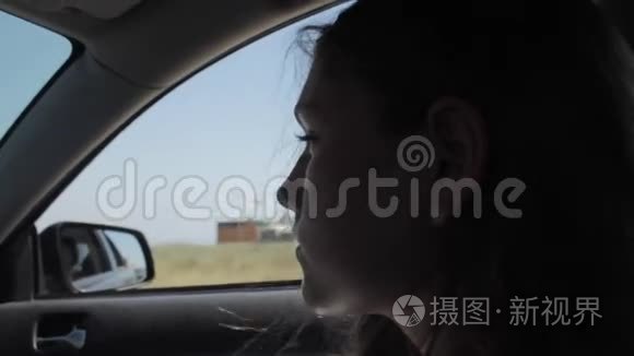 风吹过女孩的剪影和头发在车里。