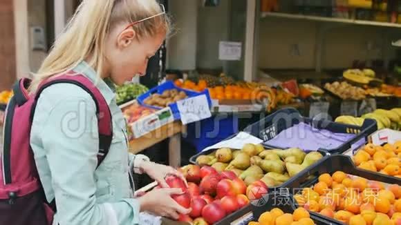在街头市场上检查水果的女人