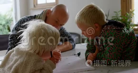 父亲帮助孩子在家画画视频